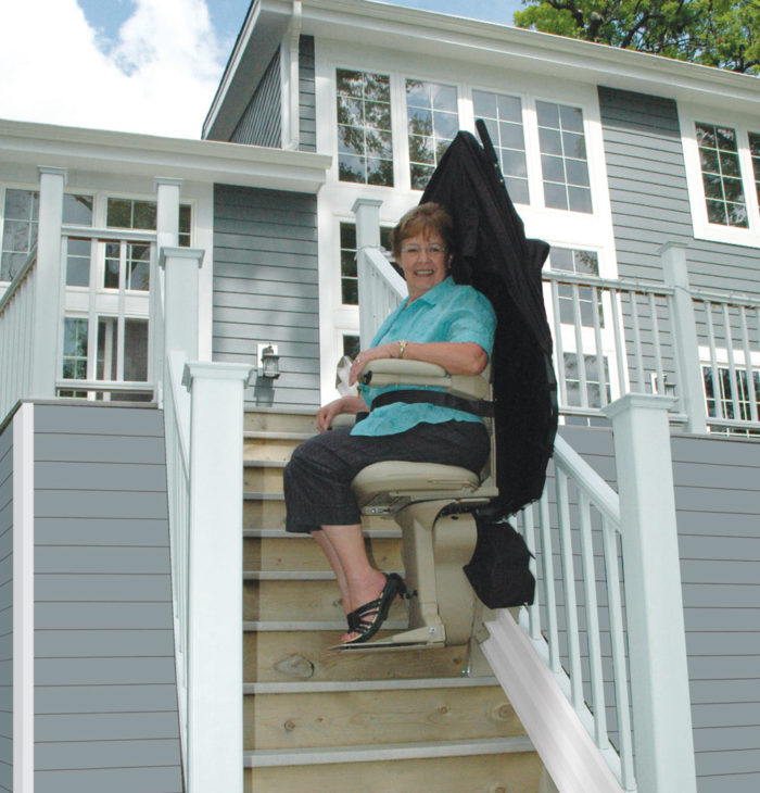 Woman riding outdoor stairlift on straight rail