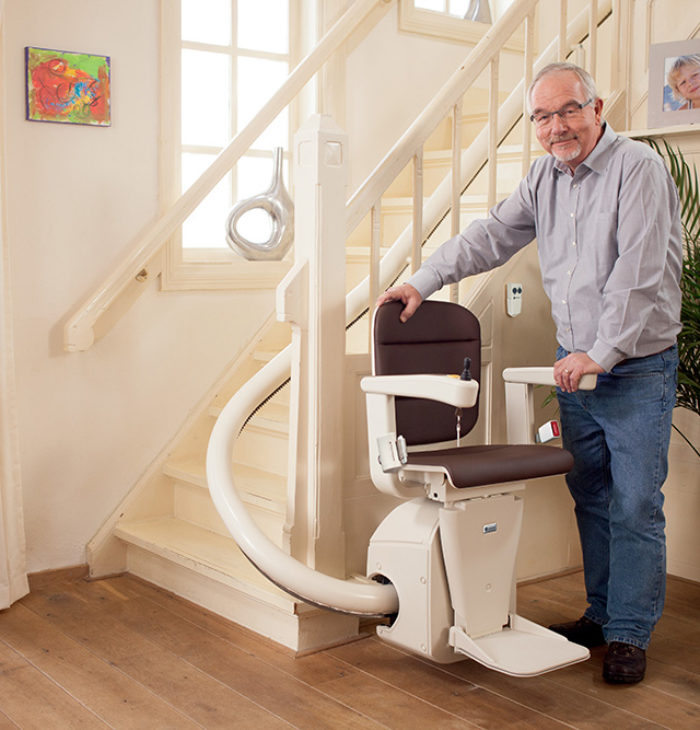 Man standing next to handicare freecurve stairlift