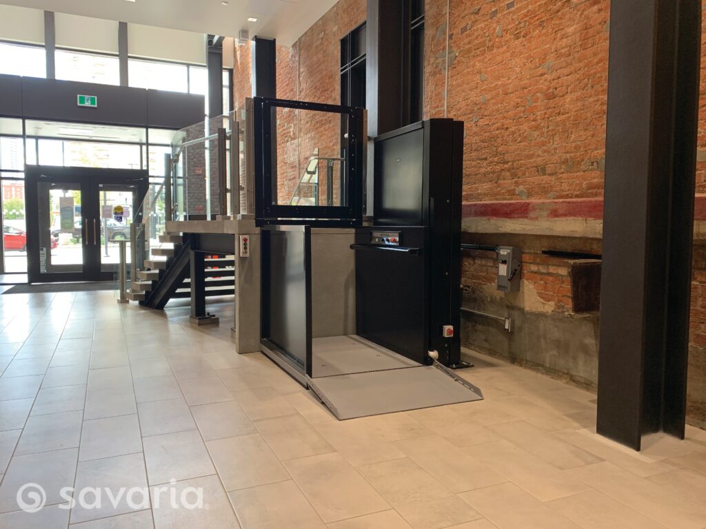 Savaria vertical platform lift at the lower landing of a commercial building lobby